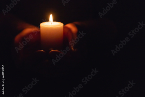 Hands holding burning candle in dark like a heart.Selective focus,black background.Copy space.