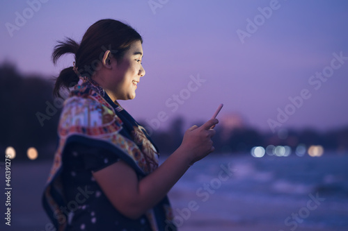 woman alone looking smartphone screen and smiling with blur city night background