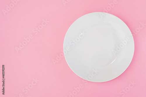 Empty white plate on pink background with copy space.