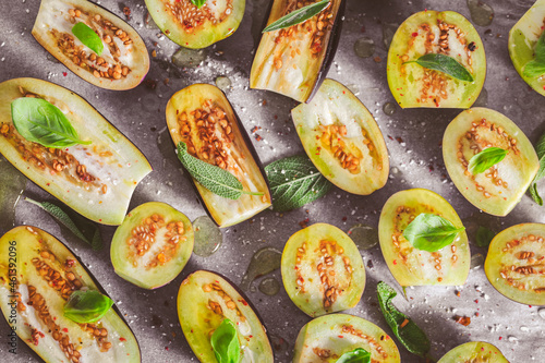 Small raw eggplants prepared for baking on baking sheet