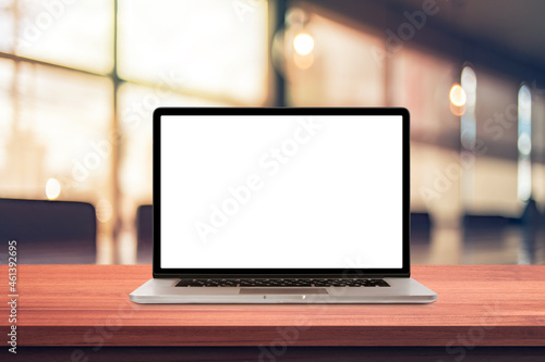 Laptop or notebook with blank screen on wood table in blurry background with coffee shop or modern office ,nature orange bokeh and sunlight in morning.vintage tone