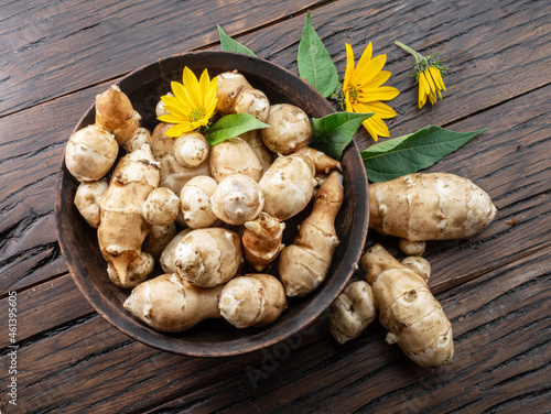 Jerusalem artichoke roots with leaves and flower of Jerusalem artichoke on a old wooden table. photo