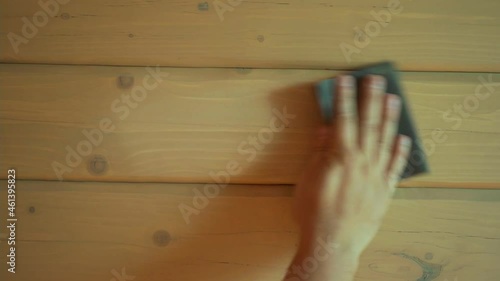 Closeup of a hand sanding wood using sandpaper.