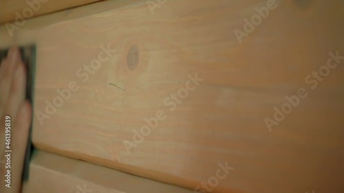 Closeup of a hand sanding wood using sandpaper.