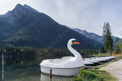 many rental boats at a bridge on lake in the mountains with a swan boat
