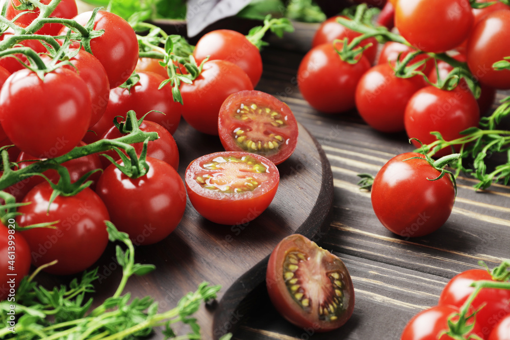Composition of fresh ripe branches of cherry tomatoes, thyme, basil, rosemary, spices on a wooden textured background Composition of fresh ripe branches of cherry tomatoes, thyme, basil, rosemary, spices on a wooden textured background