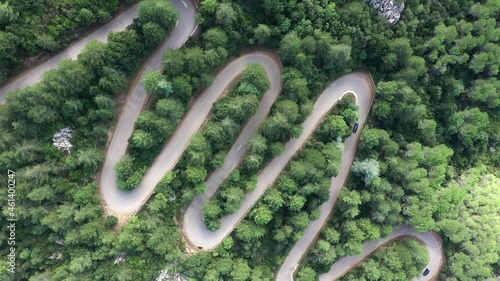 View from above, stunning aerial view of a car running along a serpentine road surrounded by green pine trees. Mount Limbara (Monte Limbara) Sardinia, Italy	 photo