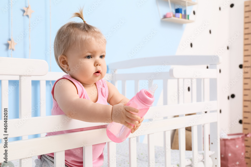 Cute baby girl with bottle of water in cot Cute baby girl with bottle of water in cot