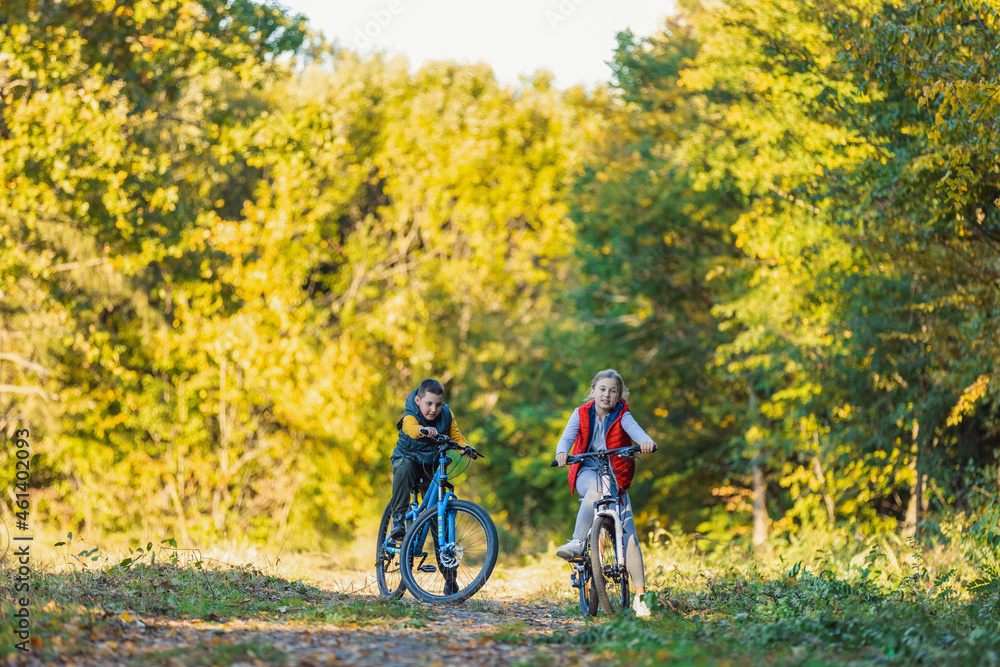 Fototapeta premium happy kids ride a bike in the autumn forest