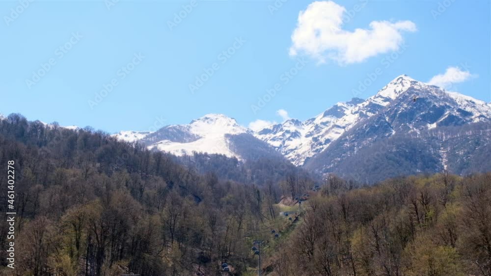 picturesque landscape of snow-capped mountains with white clouds on a blue sky on a sunny day at Krasnaya Polyana in Sochi, Russia picturesque landscape of snow-capped mountains with white clouds on a blue sky on a sunny day at Krasnaya Polyana in Sochi, Russia