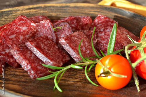 Russian cuisine: dry sausage, sliced salami on wooden board close up