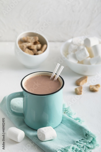 Cup of hot cocoa drink and marshmallows on light background