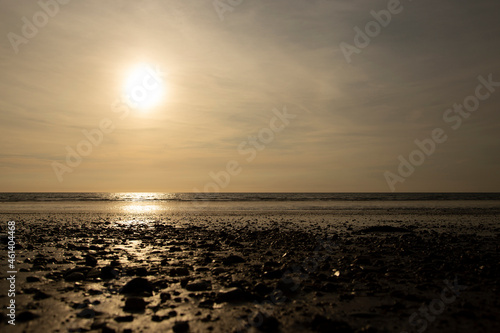 Dinas Dinlle beach with the sun setting reflected in the sea. Welsh coast beach holiday concept