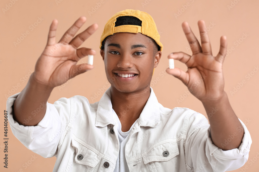 Young African-American guy with chewing gum on color background Young African-American guy with chewing gum on color background