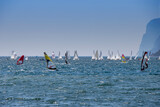 Windsurfer surfing and sailboats sailing the wind on waves In lake Lago di Garda