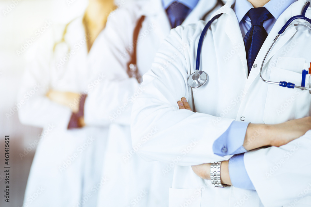 Group of modern doctors standing as a team with crossed arms and stethoscopes in a sunny hospital office. Physicians ready to examine and help patients. Medical help, insurance in health care, best Group of modern doctors standing as a team with crossed arms and stethoscopes in a sunny hospital office. Physicians ready to examine and help patients. Medical help, insurance in health care, best