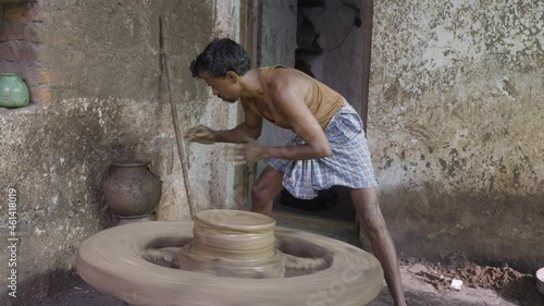 Potter giving pot form to clay on rotating traditional cart wheel - concept of small businesses, villages artists and making of earthenwares photo