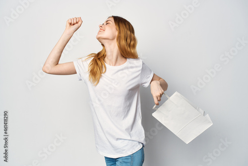 woman in a white t-shirt with a package in her hands a gift Shopping light background