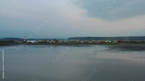 Cinematic aerial dolly in above beautiful scenic tidal flat toward heritage lighthouse building at the shore at Gaomei wetlands preservation area, Taichung, Taiwan. photo