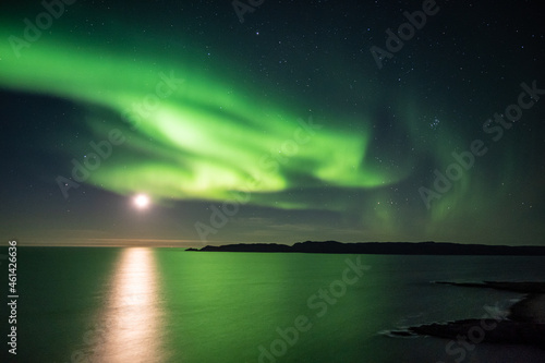 Bright green nortern lights on the shore of Baltic sea in Teriberka © Elena