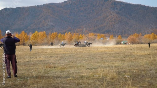 National traditional horseback game of Asian people - Buzkashi, kokpar or kupkari. Male riders on horses play match game in teams. Altai highland valley, steppes on background. Ulak tartysh polo sport photo