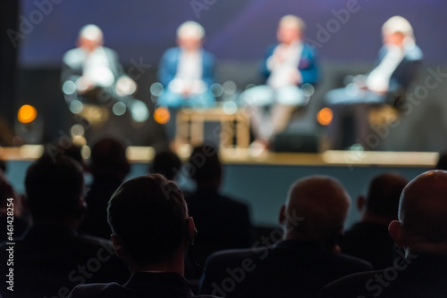 The head of the listener with the receiver in the ear, in the background the silhouettes of people conducting the conference