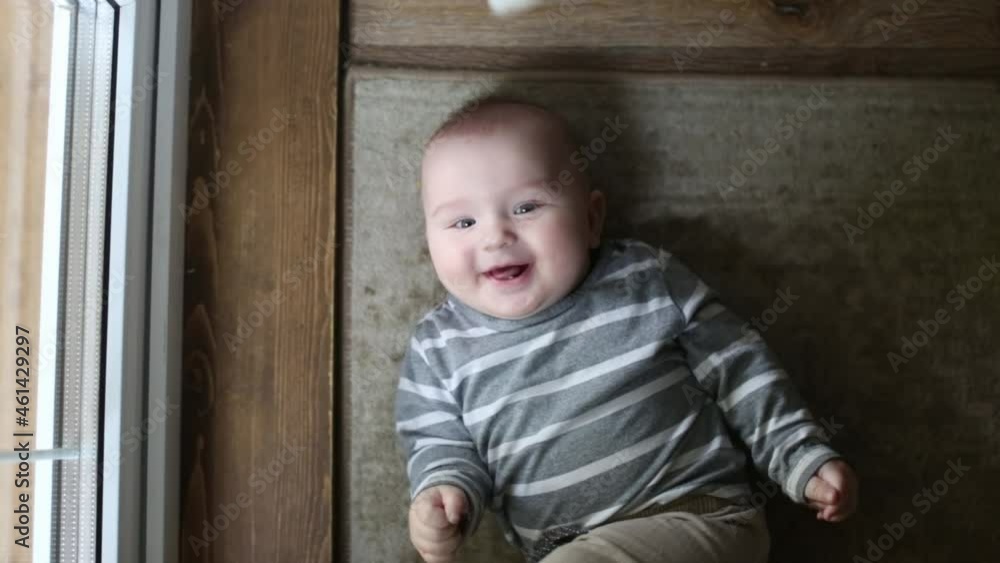 Cute laughing caucasian baby 5 6 months old lying on his back on a blanket, dark style Cute laughing caucasian baby 5 6 months old lying on his back on a blanket, dark style