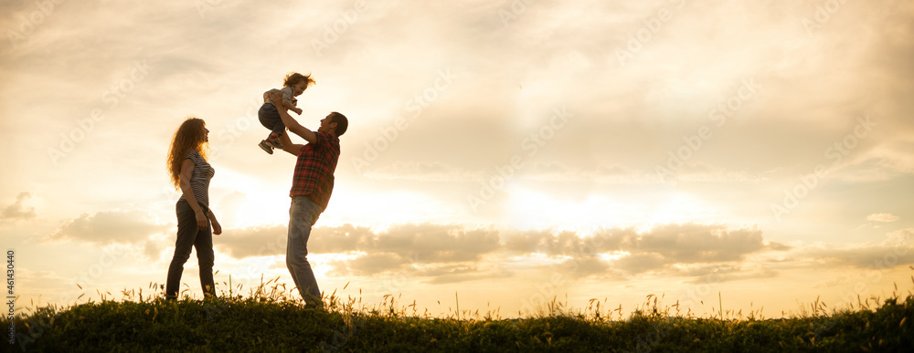 Caucasian family mom dad and little son at sunset. Silhouettes of parents and toddler boy on the background of the sky Freedom and an active lifestyle - obrazy, fototapety, plakaty 
