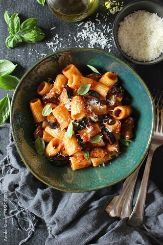 Pasta alla norma - Italian pasta with eggplante, tomato sauce and parmesan cheese on dark table. Top view. Healthy food.