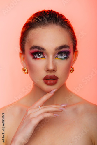 Beauty woman portrait. Professional makeup for model with blue eyes and big plump lips. Red lipstick, colored smoky eyes. Isolated on a pink background.
