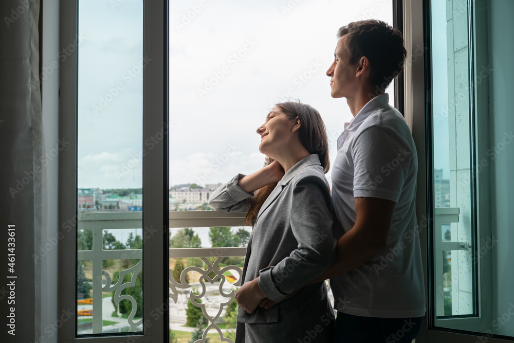 Young couple stands near window and enjoys weekend in hotel room Young couple stands near window and enjoys weekend in hotel room