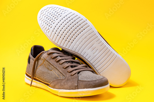 Man's new sneakers made of brown canvas, beautifully laid out on a yellow background. Close up