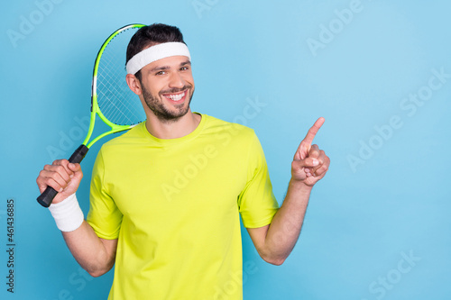 Photo of cheerful happy young man tennis player point finger empty space news smile isolated on blue color background photo
