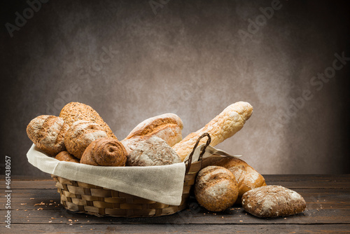 assortment of baked bread in straw basket on wooden table