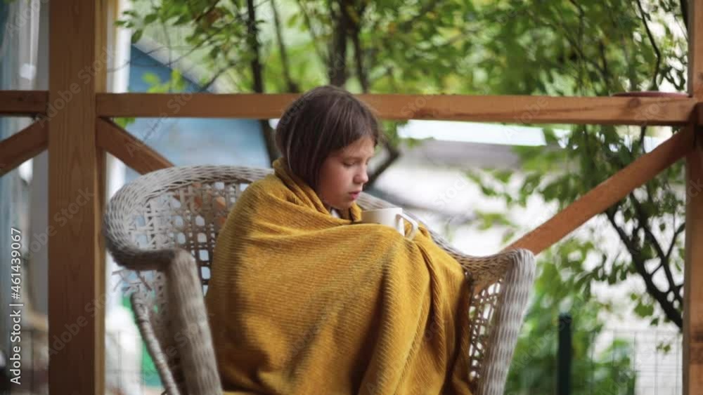 Cute pensive caucasian preteen girl with a cup of hot drink wrapping in knitting yellow plaid on the veranda, Stock-Video | Adobe Stock 