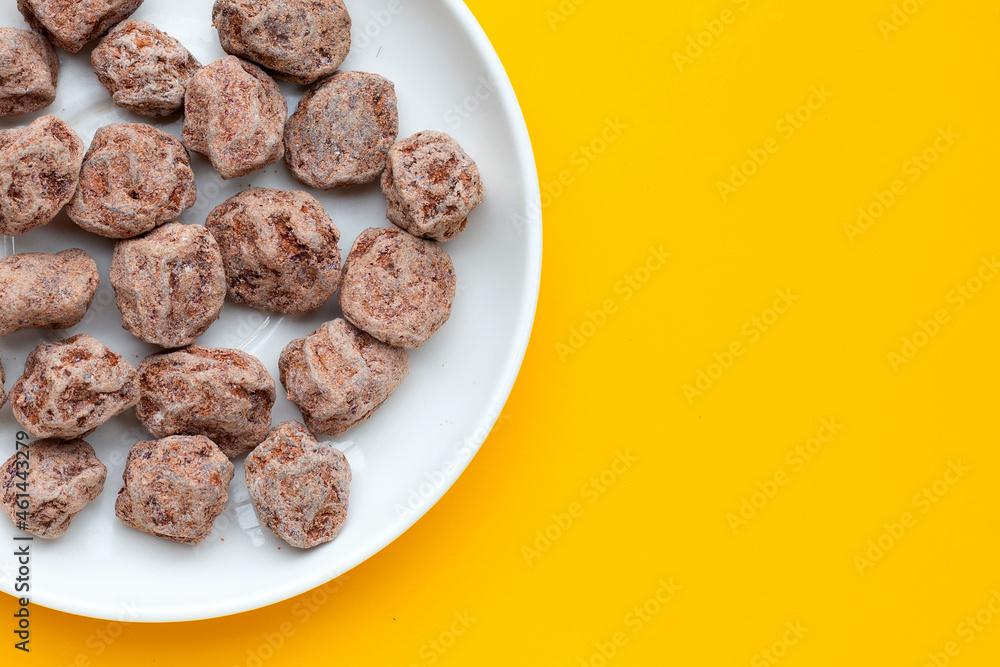 Dried salted Chinese plum in white plate on yellow background