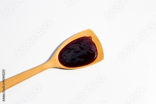 Oyster sauce in wooden spatula on white backgroound.