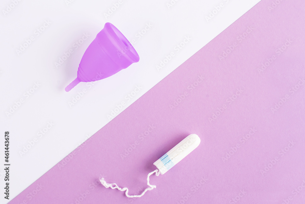 Silicone menstrual cup and tampon. Women's health and alternative hygiene, zero waste alternatives, female intimate hygiene period products, critical days. Top view, White and violet Silicone menstrual cup and tampon. Women's health and alternative hygiene, zero waste alternatives, female intimate hygiene period products, critical days. Top view, White and violet