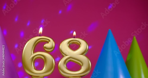 Burning birthday cake candle number 68. Happy Birthday background anniversary celebration concept. Birthday hat in the background photo