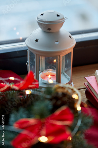 winter holidays, new year and decorations concept - close up of candle burning in christmas lantern on window sill at home
