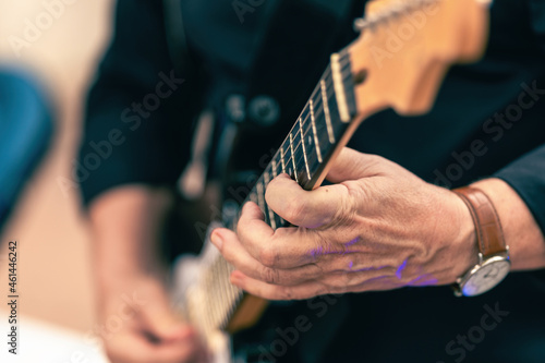 Aged hand of a musician playing an electric guitar outdoors
