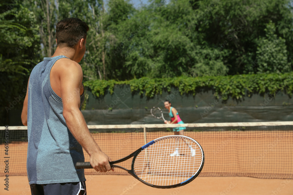 Couple playing tennis on court during sunny day