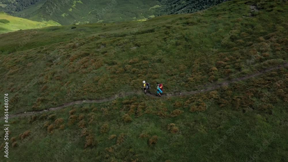 Two hikers with backpacks are walking along mountain range in Carpathian mountains Two hikers with backpacks are walking along mountain range in Carpathian mountains