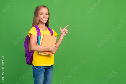 Portrait of pretty cheerful girl holding college books showing copy space isolated over vivid green color background