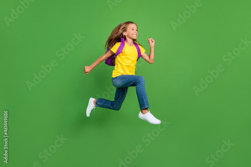 Full length body size view of pretty motivated cheerful girl learner jumping running isolated over bright green color background