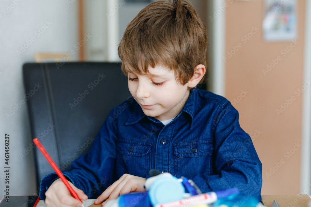Hard-working school kid boy making homework during quarantine time from corona pandemic disease. Child on home schooling in coronavirus covid time, schools closed. Homeschooling concept
