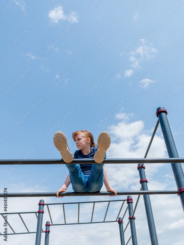Young girl climbs the bar on the playground. Child sports concept. Healthy lifestyle. Young girl climbs the bar on the playground. Child sports concept. Healthy lifestyle.