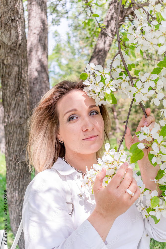 Young woman stands in the park next to a flowering tree. Spring time. Young woman stands in the park next to a flowering tree. Spring time.
