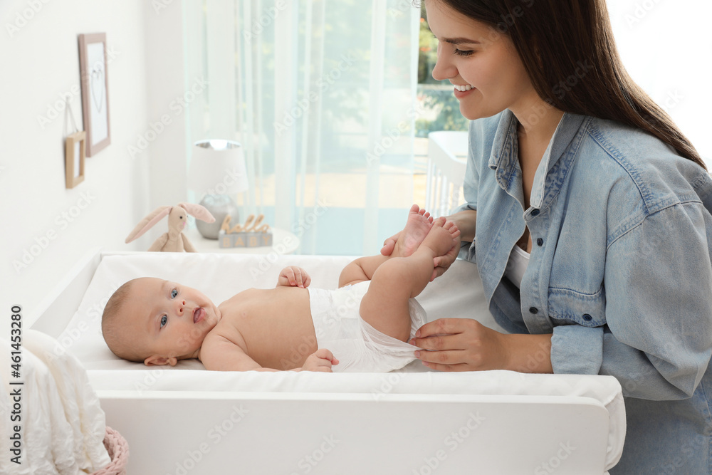 Mother changing her baby's diaper on table at home Mother changing her baby's diaper on table at home