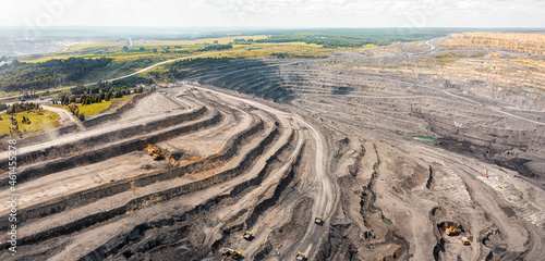 Panoramic aerial view of coal mine. Open pit mine industry, big yellow mining truck for coal quarry. Open coal mining anthracite mining. Pit on coal mining by open way. Rock loading in trucks